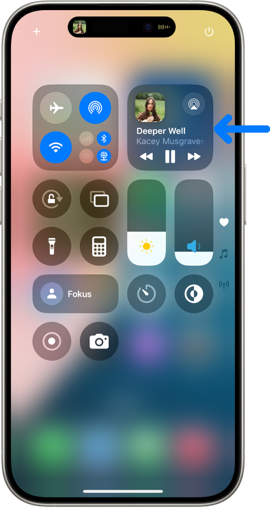 Pusat Kawalan iPhone menunjukkan anak panah menuding ke kad audio di tempat anda boleh mengawal muzik daripada Skrin Kunci atau semasa menggunakan app lain.