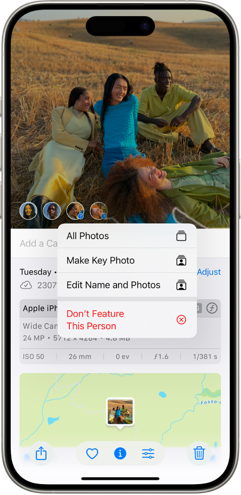 The top half of the iPhone screen shows a photo open in the Photos app. In the bottom-left corner of the photo are question marks next to the people and pets that appear in the photo. A question mark is selected and a menu of options includes, from top to bottom, Name This Person, All Photos, Make Key Photo, Edit Name and Photos, and Feature This Person Less.
