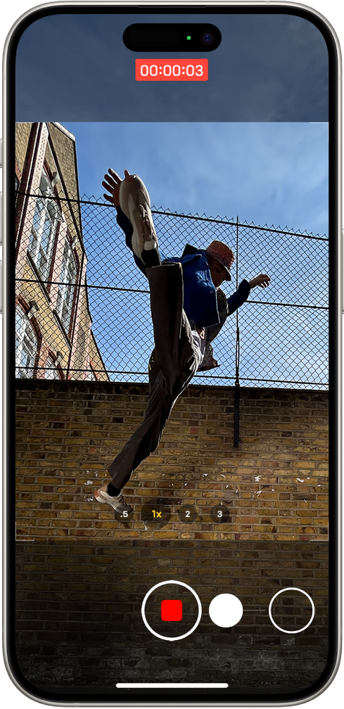 La pantalla de la app Cámara en el modo Foto. El sujeto llena el centro de la pantalla, dentro del cuadro de la cámara. En el área inferior de la pantalla, se mueve el botón Obturador a la derecha para ilustrar el movimiento para empezar a grabar un video QuickTake. El indicador de grabación se encuentra en la parte superior de la pantalla.