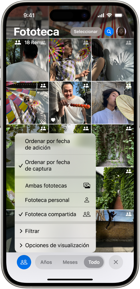 Fototeca compartida en iCloud en la app Fotos. El botón “Fototeca compartida” de la esquina inferior izquierda está seleccionado y se ha seleccionado “Fototeca compartida” de una lista de opciones de fototeca. Todas las fotos mostradas en la fototeca tienen un indicador de fototeca compartida en la esquina superior derecha.